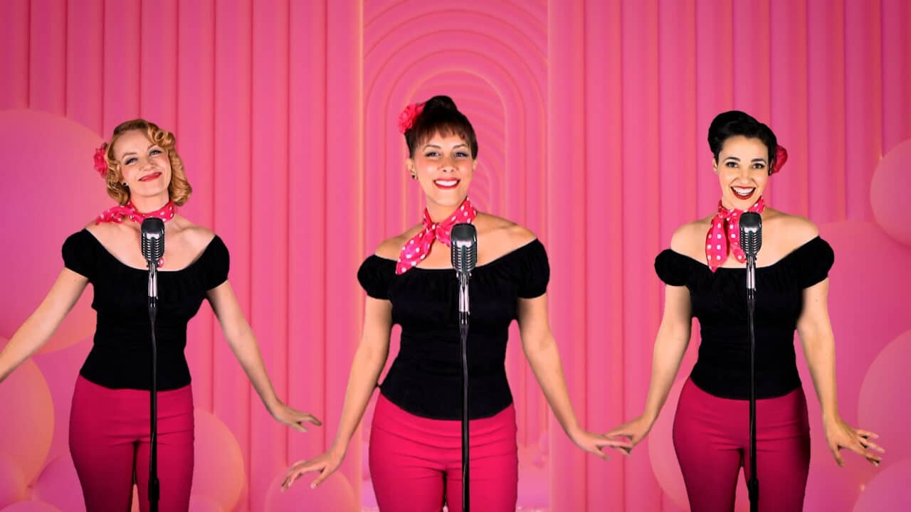 The Sweethearts performing a hit song from the 1950s in front a virtual backdrop
